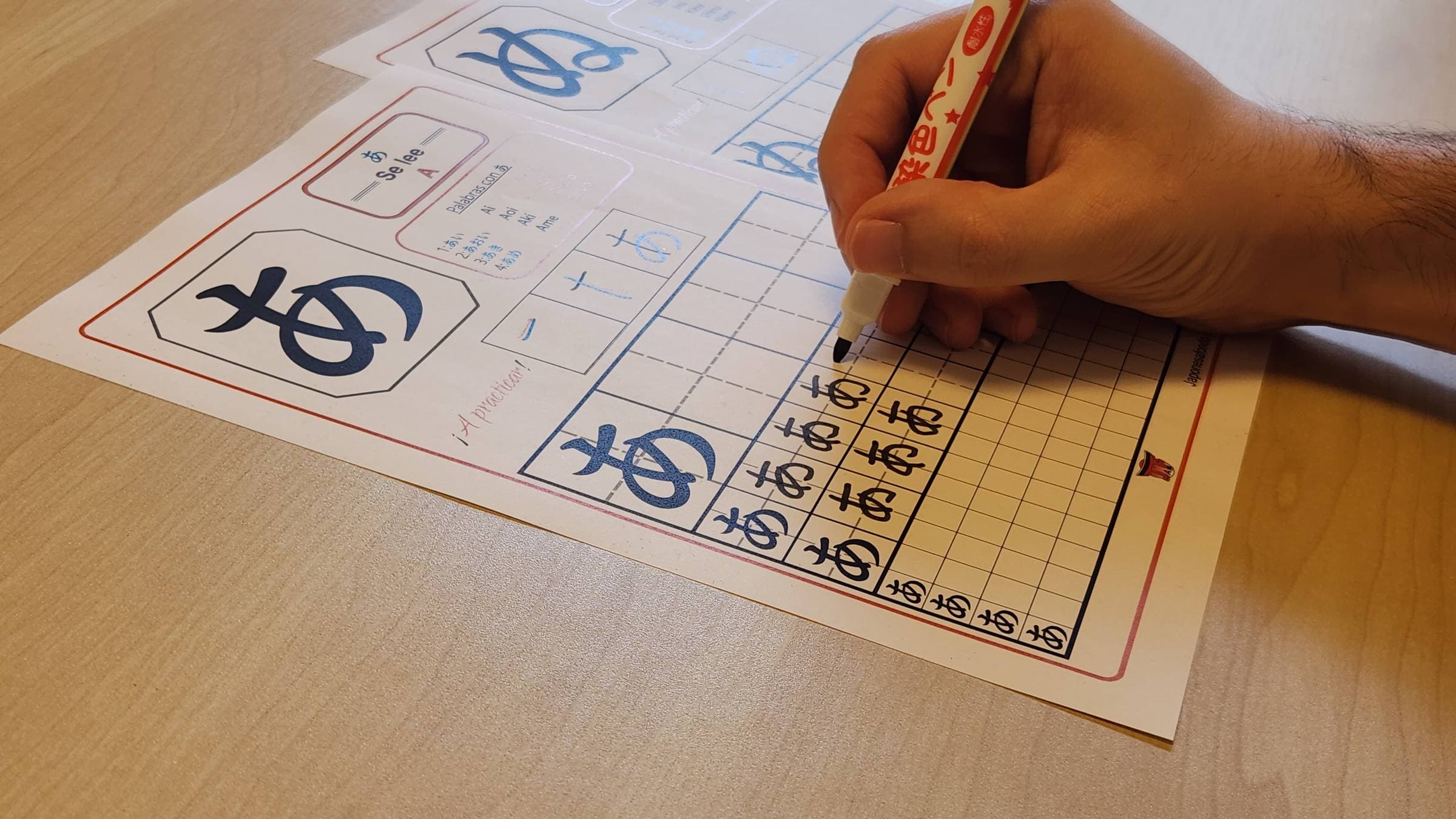 Cuaderno de Hiragana impreso, practicando el carácter あ con rotulador